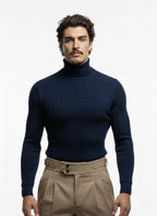 Man wearing a navy turtleneck sweater and beige pants on a white background