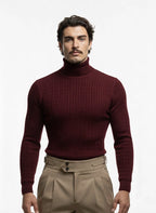 Man wearing a maroon turtleneck sweater and beige pants on a white background