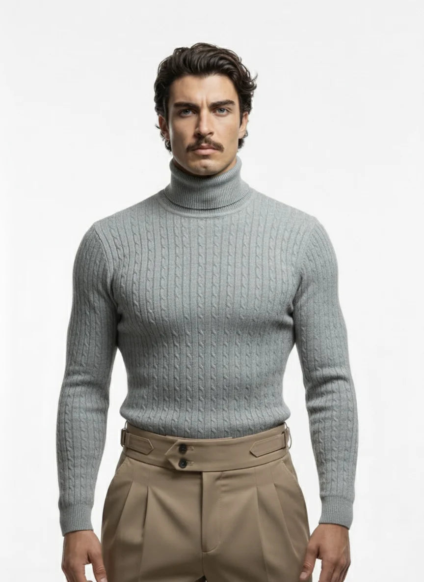 Man wearing a light gray turtleneck sweater and beige pants on a white background
