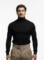 Man wearing a black turtleneck and beige pants on a white background
