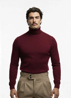 Man wearing a burgundy turtleneck sweater and beige pants on a white background