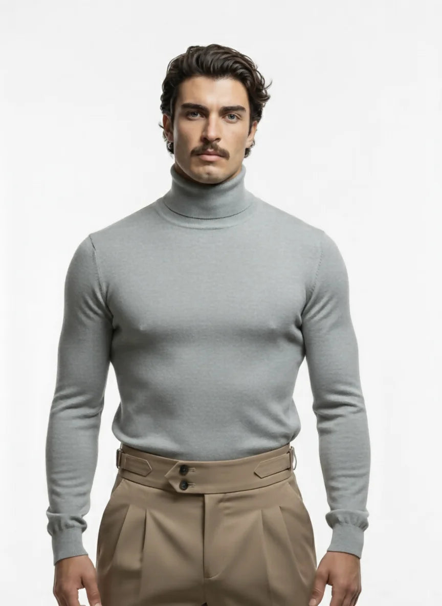 Man wearing a gray turtleneck sweater and beige pants on a white background